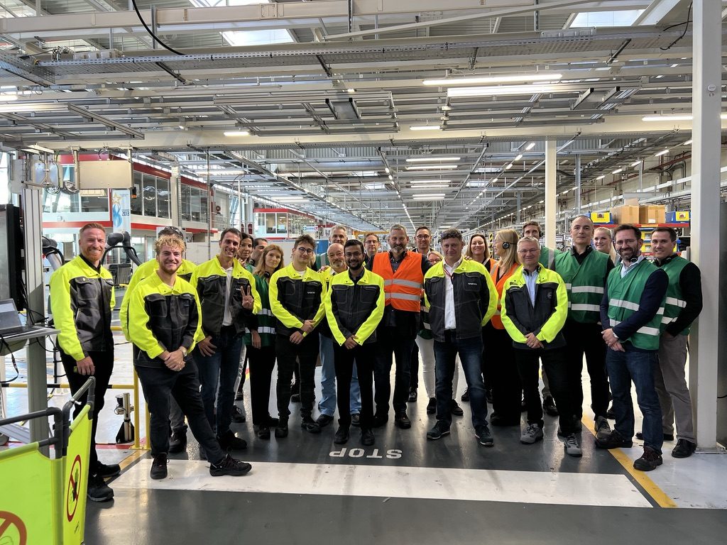 A group in high-visibility jackets on a production line